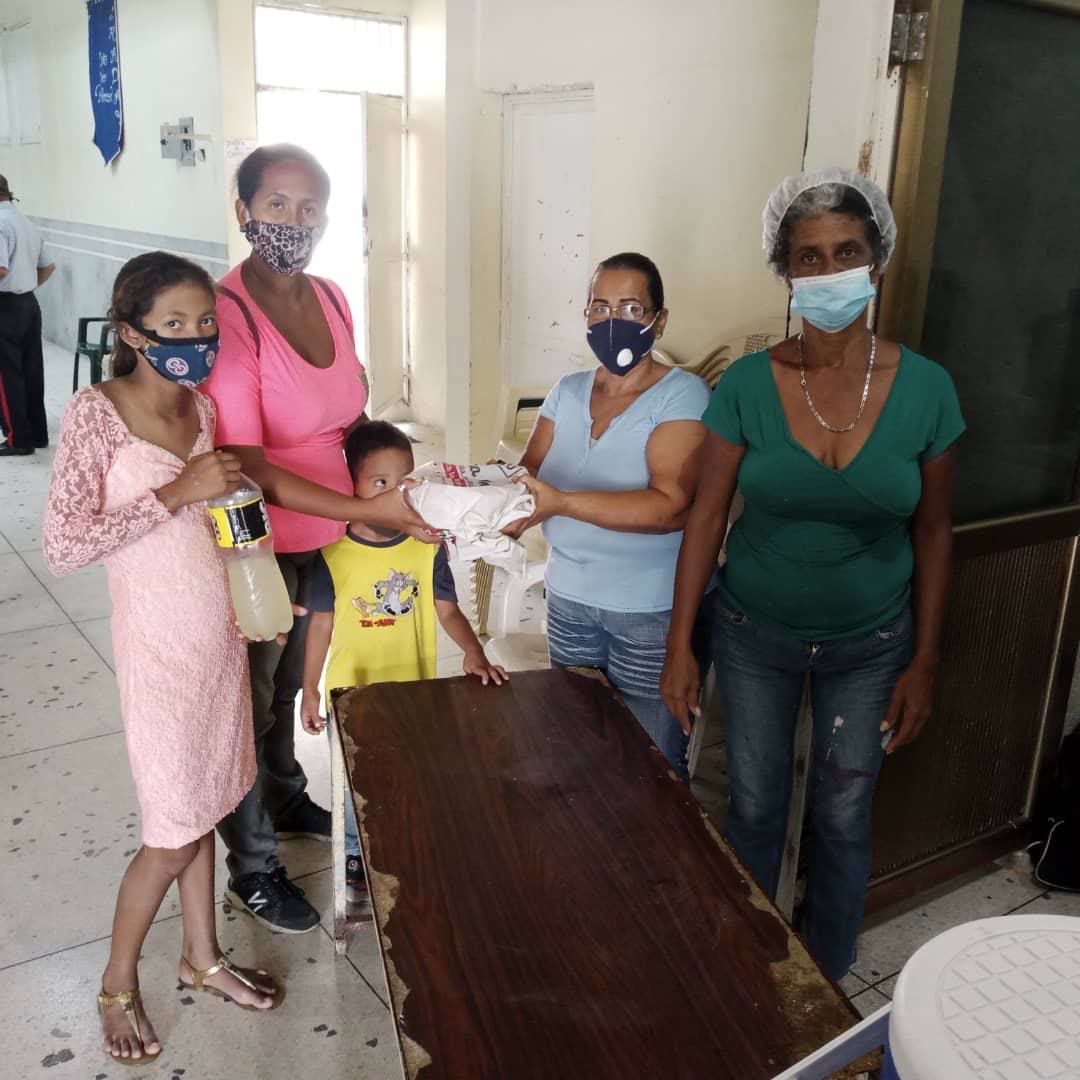 Voluntarias de la fundación entregan alimentos a una familia durante una jornada.