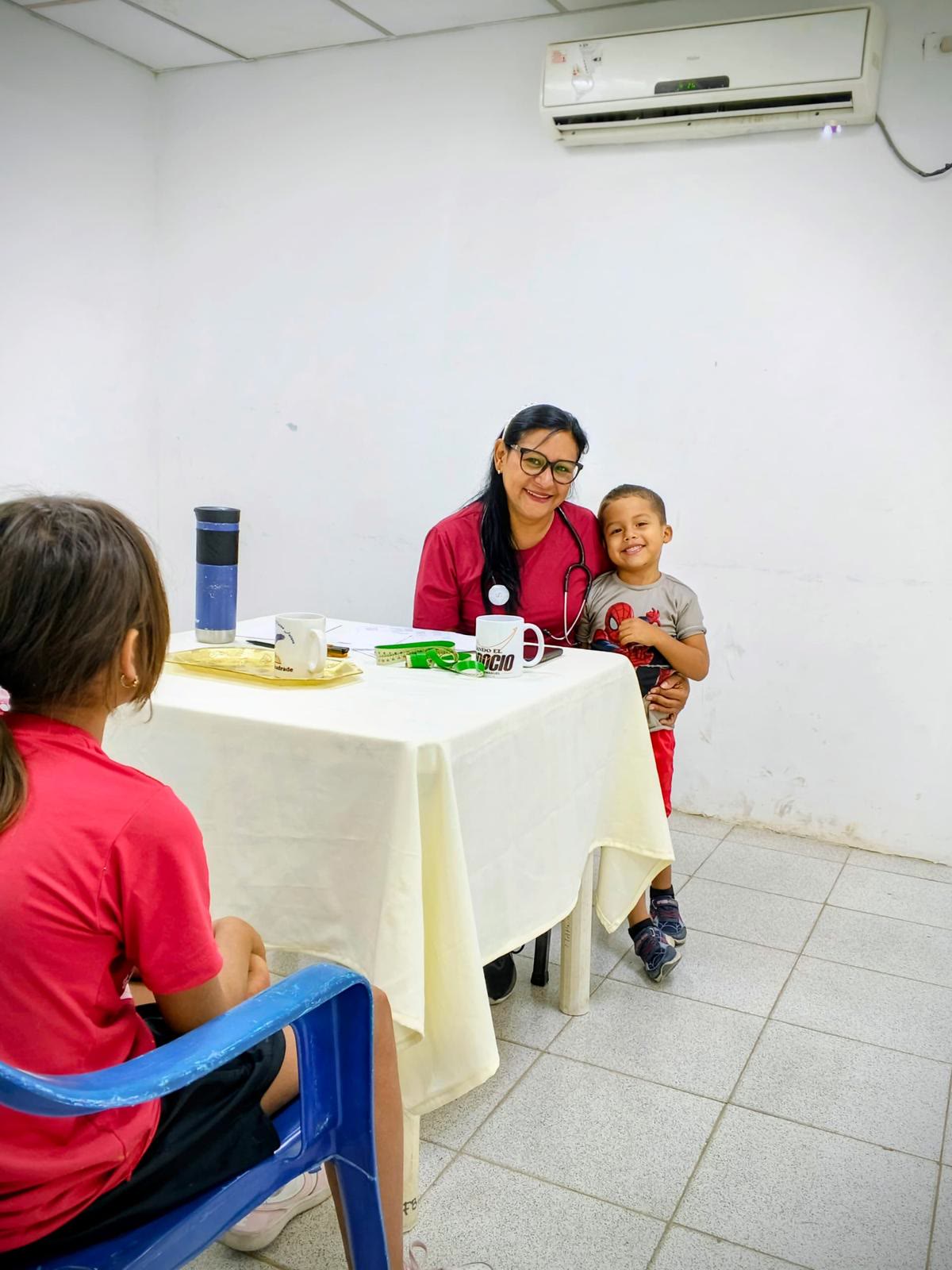 Una doctora voluntaria acompaña a un niño durante una consulta de salud.