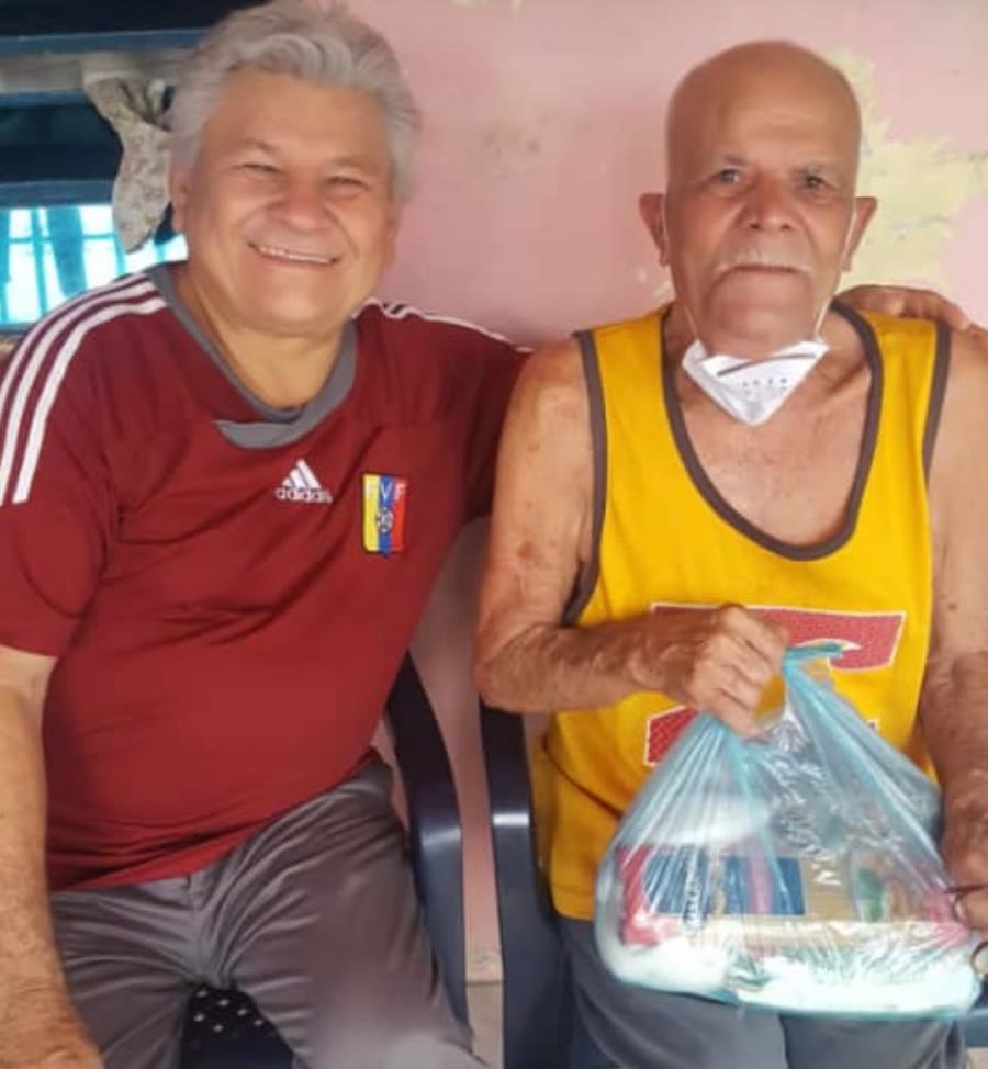Euclides Chirinos, fundador de la Fundación Abrazos de Amor, junto a un vecino durante una entrega de alimentos.