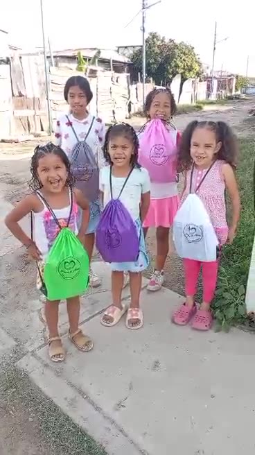 Niñas muestran felices los kits escolares que acaban de recibir.